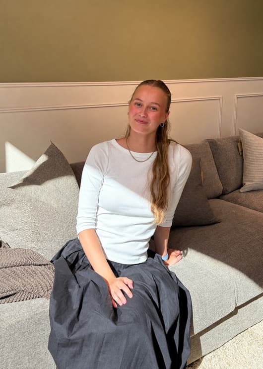 Hannah Prestegård sitting on a sofa in a white shirt